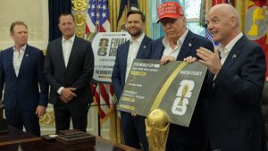 Presiden FIFA, Gianni Infantino, berbincang sambil memegang replika tiket Piala Dunia berukuran besar bersama Presiden AS, Donald Trump, di Ruang Oval, sementara Wakil Presiden, JD Vance (ketiga dari kiri), mengamati pada 22 Agustus 2025 di Washington, DC.