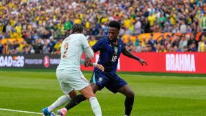 Malo Gusto dan Vinicius Junior berebut bola dalam laga uji coba internasional antara Brasil vs Prancis di Gillette Stadium, Massachusetts, 27 Maret 2026. (AP Photo/Charles Krupa)